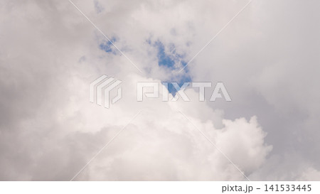 Bright towering white clouds open across soft blue sky, forming airy atmospheric backdrop with gentle daylight, soft texture, calm weather, serene mood, and expansive open space 141533445