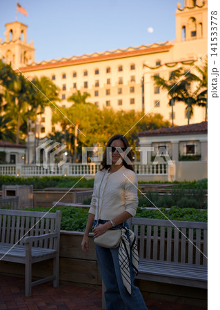 Smiling Woman Standing By A Garden Bench Near A Historic Hotel Smiling Woman Standing By A Garden Bench Near A Historic Hotel 141533778