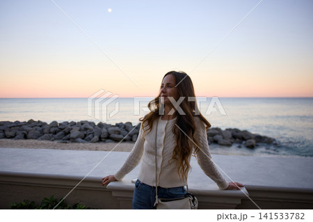 Carefree Woman Stretches Her Arms By The Sea At Dusk Carefree Woman Stretches Her Arms By The Sea At Dusk 141533782