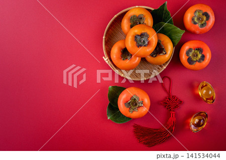 Persimmons on Red Background with Lunar New Year Decorations Persimmons on Red Background with Lunar New Year Decorations 141534044