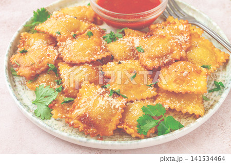 fried ravioli with parmesan cheese, served with red sauce and garnished with herbs, on a light background, no people, 141534464