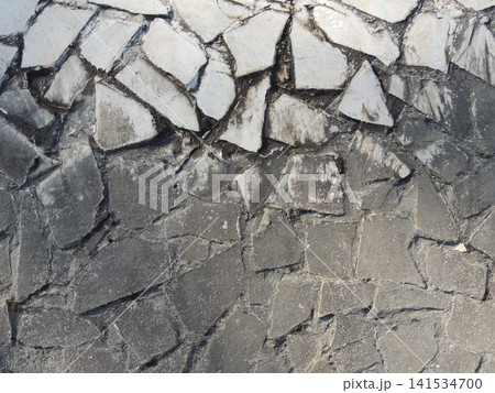 Two-tone cladding made of wild stone. The upper tier is formed from flat fragments of white flagstone with jagged edges, while the massive base is laid with a mosaic of rough gray blocks and mortar. Two-tone cladding made of wild stone. The upper tier is formed from flat fragments of white flagstone with jagged edges, while the massive base is laid with a mosaic of rough gray blocks and mortar. 141534700