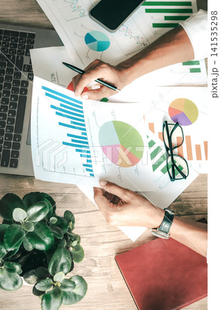 Businessperson studies colorful data charts in a tidy office Businessperson studies colorful data charts in a tidy office 141535298