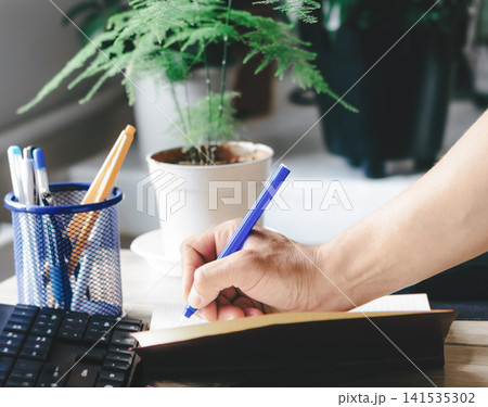 A man writes in a notebook and makes a business plan A man writes in a notebook and makes a business plan 141535302