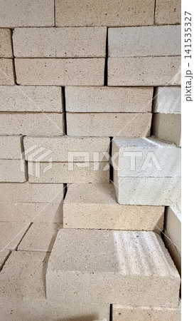 Close-up of stacked refractory bricks or fireclay blocks with rough beige surface in industrial storage. 141535327
