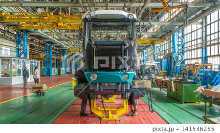 Conveyor assembly stage the body of tractor at big industrial factory timelapse Conveyor assembly stage the body of tractor at big industrial factory timelapse 141536285