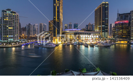 Aerial view of Dubai Marina with shopping mall, restaurants, towers and yachts day to night timelapse, United Arab Emirates. Aerial view of Dubai Marina with shopping mall, restaurants, towers and yachts day to night timelapse, United Arab Emirates. 141536409