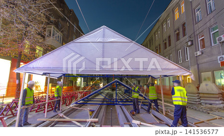 Builders making tent cover over tram rails at the stage of their installation on the road timelapse. Builders making tent cover over tram rails at the stage of their installation on the road timelapse. 141536577