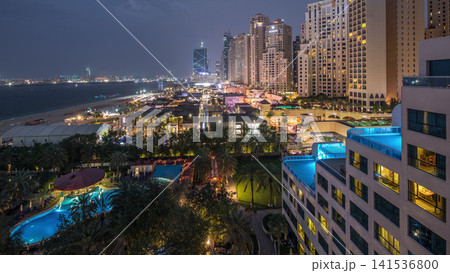 Aerial view of beach and tourists walking in JBR with skyscrapers day to night timelapse in Dubai, UAE Aerial view of beach and tourists walking in JBR with skyscrapers day to night timelapse in Dubai, UAE 141536800