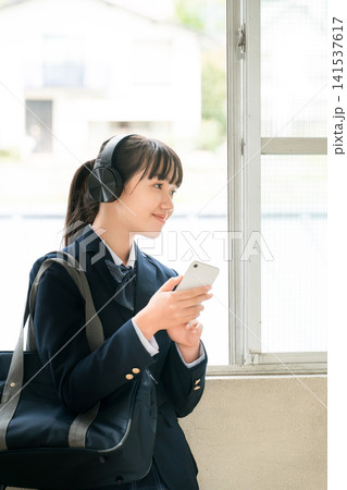 学校の廊下でヘッドフォンで音楽を聴く制服姿の小学生,中学生,高校生の女の子 学校の廊下でヘッドフォンで音楽を聴く制服姿の小学生,中学生,高校生の女の子 141537617