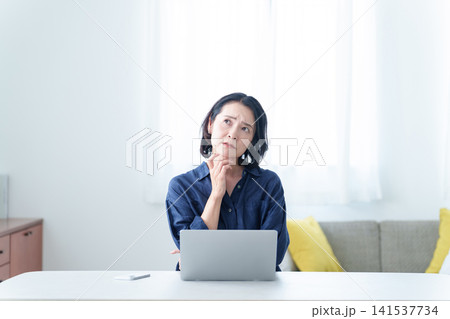 デスクワーク中に困った表情をする中高年女性 141537734