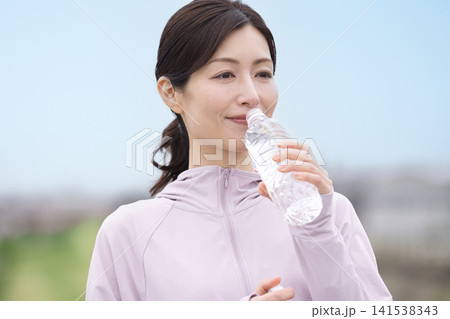 ウォーキング中にペットボトルの水を飲むミドル女性 ウォーキング中にペットボトルの水を飲むミドル女性 141538343