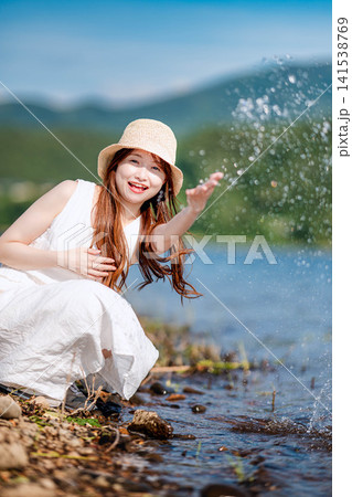 湖畔で水しぶきを上げて遊ぶ女性 141538769