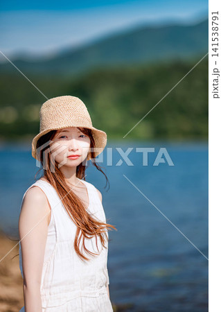 夏の湖を背景に微笑む白ワンピースの女性 夏の湖を背景に微笑む白ワンピースの女性 141538791