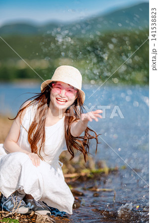 きらめく水辺ではしゃぐ麦わら帽子の女性 きらめく水辺ではしゃぐ麦わら帽子の女性 141538823