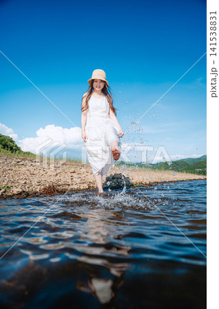 夏の湖で水しぶきを上げて歩く白ワンピースの女性 夏の湖で水しぶきを上げて歩く白ワンピースの女性 141538831