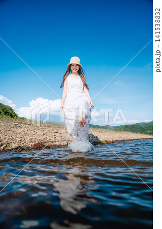 浅瀬を歩いて水遊びをする麦わら帽子の女性 浅瀬を歩いて水遊びをする麦わら帽子の女性 141538832