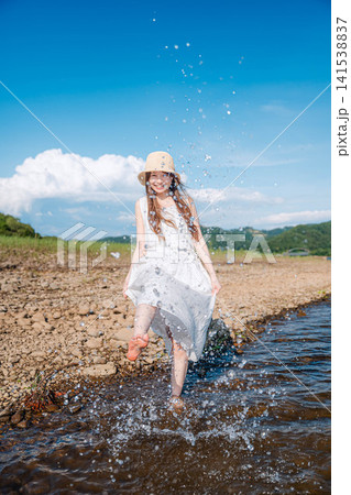 湖の浅瀬で裾を持ち歩く麦わら帽子の女性 湖の浅瀬で裾を持ち歩く麦わら帽子の女性 141538837