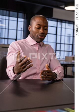 African american man presenting near grid-window conference table and checking watch African american man presenting near grid-window conference table and checking watch 141539190