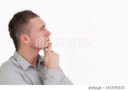 Man in twenties posing with hand on chin in studio wearing gray button-up shirt, copy space Man in twenties posing with hand on chin in studio wearing gray button-up shirt, copy space 141540315