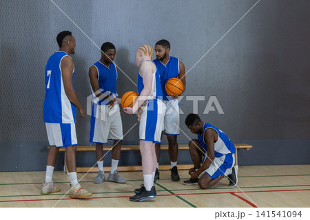 African american male teammates with basketballs standing by bench on court discussing strategy African american male teammates with basketballs standing by bench on court discussing strategy 141541094