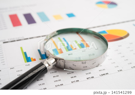 Magnifying glass on spreadsheet and graph paper. Financial data economy, Business. 141541299