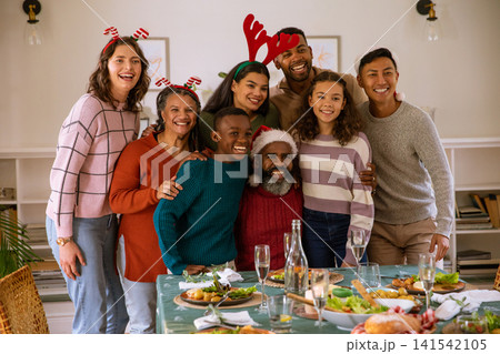 Diverse extended family celebrating meal in dining room at dining table with candles, headbands 141542105