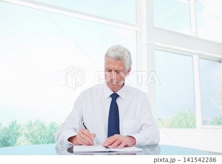 Senior male sitting at table in office writing documents with pen wearing white shirt and tie Senior male sitting at table in office writing documents with pen wearing white shirt and tie 141542286