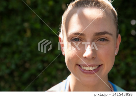 Woman smiling while standing in garden in athletic top with headband stud earrings, copy space 141543959