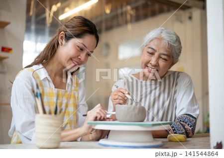 Asian women different generations working together on pottery enjoying creative workshop with smiles Asian women different generations working together on pottery enjoying creative workshop with smiles 141544864