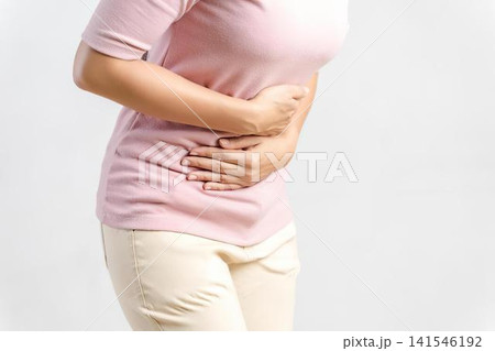 Woman in pink shirt holding stomach pain in white background Woman in pink shirt holding stomach pain in white background 141546192