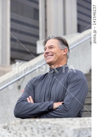 Senior man standing on stairs near railing, crossing arms, smiling, looking left in zipup pullover Senior man standing on stairs near railing, crossing arms, smiling, looking left in zipup pullover 141546237