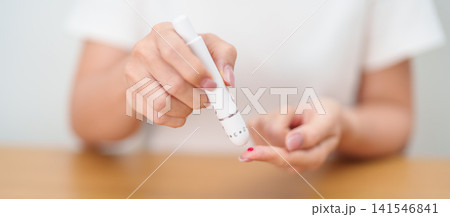 Hand using lancet pen on finger with Blood drop glucose testing or Diabetes checking by digital blood glucose meter. blood sugar level, Diabetes Day, Glycemia, Hypoglycemia, Hyperglycemia and insulin 141546841