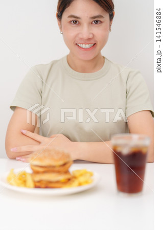 happy woman with Juicy beef burger with melted cheddar cheese, potato chips and carbonated Soft drinks. Unhealthy, High calorie, Fast food craving, Obesity, diet, weight loss, junk food and lifestyle happy woman with Juicy beef burger with melted cheddar cheese, potato chips and carbonated Soft drinks. Unhealthy, High calorie, Fast food craving, Obesity, diet, weight loss, junk food and lifestyle 141546884