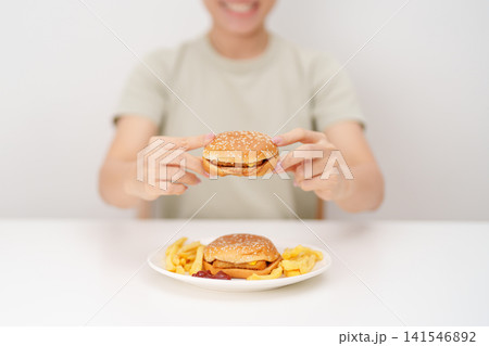 happy woman eating Juicy beef burger with melted cheddar cheese, potato chips. Unhealthy, High calorie, Fast food craving, Obesity, diet, weight loss, junk food and lifestyle 141546892