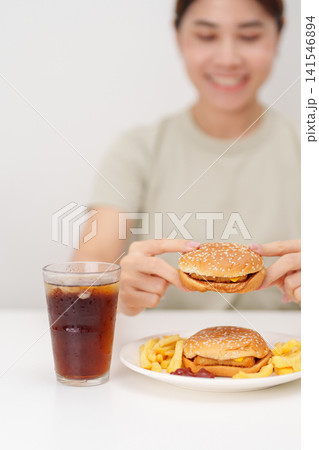 woman eating Juicy beef burger with melted cheddar cheese, potato chips and carbonated Soft drinks. Unhealthy, High calorie, Fast food craving, Obesity, diet, weight loss, junk food and lifestyle woman eating Juicy beef burger with melted cheddar cheese, potato chips and carbonated Soft drinks. Unhealthy, High calorie, Fast food craving, Obesity, diet, weight loss, junk food and lifestyle 141546894