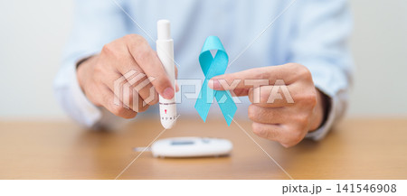Hand show Blue Ribbon and digital blood glucose meter with lancet pen. high blood sugar level, November World Diabetes Day, Awareness month, Glycemia,, Hyperglycemia and insulin testing and checking 141546908