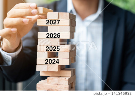 2027 year Goals, Business planning, Risk Management, Solution and strategy Concepts. Businessman hand placing or pulling wooden block on the tower 2027 year Goals, Business planning, Risk Management, Solution and strategy Concepts. Businessman hand placing or pulling wooden block on the tower 141546952