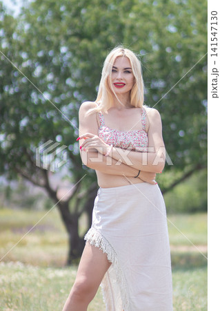 Outdoor fashion portrait of one adult woman smiling with crossed arms and direct gaze. Useful for confidence, beauty, summer clothing, and lifestyle content. Outdoor fashion portrait of one adult woman smiling with crossed arms and direct gaze. Useful for confidence, beauty, summer clothing, and lifestyle content. 141547130