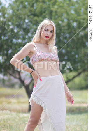 Outdoor portrait of one adult woman posing with hand on hip in a summer outfit. Suitable for fashion, beauty, confidence, and seasonal lifestyle content. 141547180