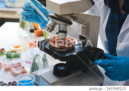 Scientists in lab coats work with plants in a modern lab, focusing on research and experimentation under bright, sterile conditions. Scientists in lab coats work with plants in a modern lab, focusing on research and experimentation under bright, sterile conditions. 141549123