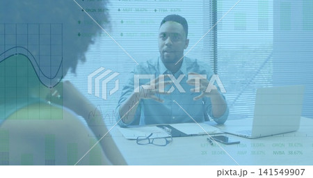 Gesturing man in light-blue shirt explaining financial charts at office desk, laptop glasses Gesturing man in light-blue shirt explaining financial charts at office desk, laptop glasses 141549907