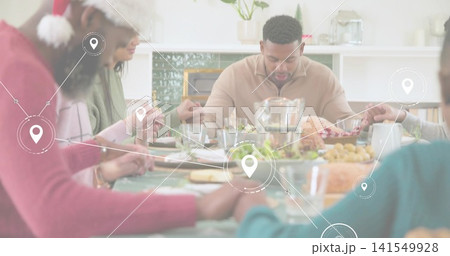 Holding hands man in beige zip sweater bowing head at dining table, roasted turkey, location pins Holding hands man in beige zip sweater bowing head at dining table, roasted turkey, location pins 141549928