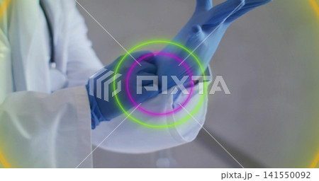 Pulling blue glove onto right hand, doctor in clinic with lab coat, stethoscope, neon rings Pulling blue glove onto right hand, doctor in clinic with lab coat, stethoscope, neon rings 141550092