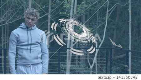 Standing man in hoodie on wooden deck by metal cable railing, watching holo disc, copy space Standing man in hoodie on wooden deck by metal cable railing, watching holo disc, copy space 141550348