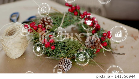 Showing handmade evergreen wreath on kraft paper, with twine spool, blue scissors, overlay icons 141550944
