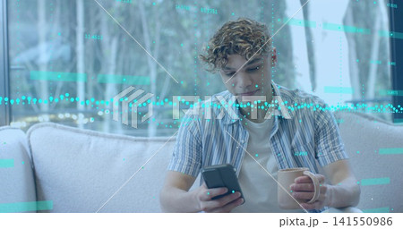 Holding smartphone and ceramic mug, man in striped shirt studying teal data overlay in home Holding smartphone and ceramic mug, man in striped shirt studying teal data overlay in home 141550986