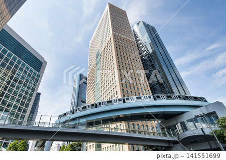 Low-angle view of a New Transit Yurikamome line train running on the elevated track with modern skyscrapers in Shiodome, Minato, Tokyo, Japan. It's an automated guideway transit service in Tokyo. Low-angle view of a New Transit Yurikamome line train running on the elevated track with modern skyscrapers in Shiodome, Minato, Tokyo, Japan. It's an automated guideway transit service in Tokyo. 141551699