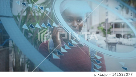 Talking on phone, woman wearing maroon sweater with backpack standing on sidewalk behind blue panel 141552077