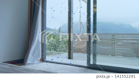 Framing sliding glass doors showing hanging rattan chair on wooden deck from bedroom, blue droplets 141552291